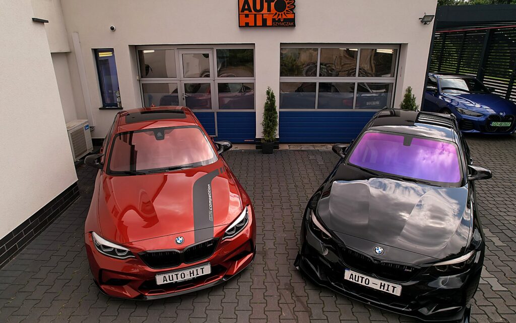 Auta BMW przed salonem Auto-Hit z szyldem - komis i serwis samochodowy